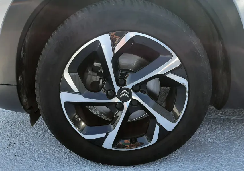 Gros plan sur la roue avant gauche du Citroën C5 Aircross gris Artense avec jante alliage noire et argentée au design moderne.