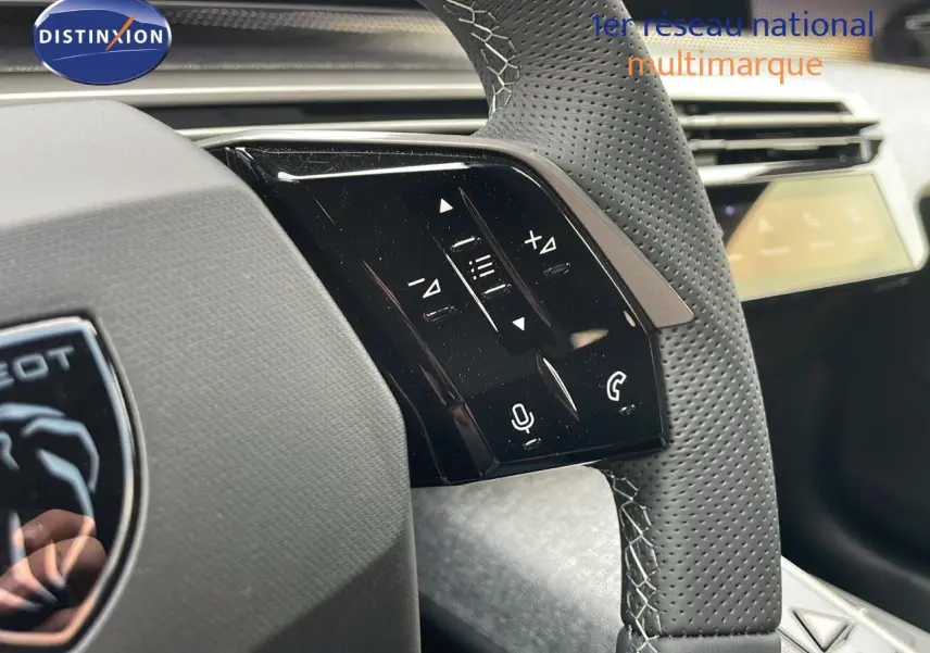 Gros plan sur le volant en cuir perforé gris du Peugeot 5008 Hybrid 2025 avec commandes tactiles intégrées.