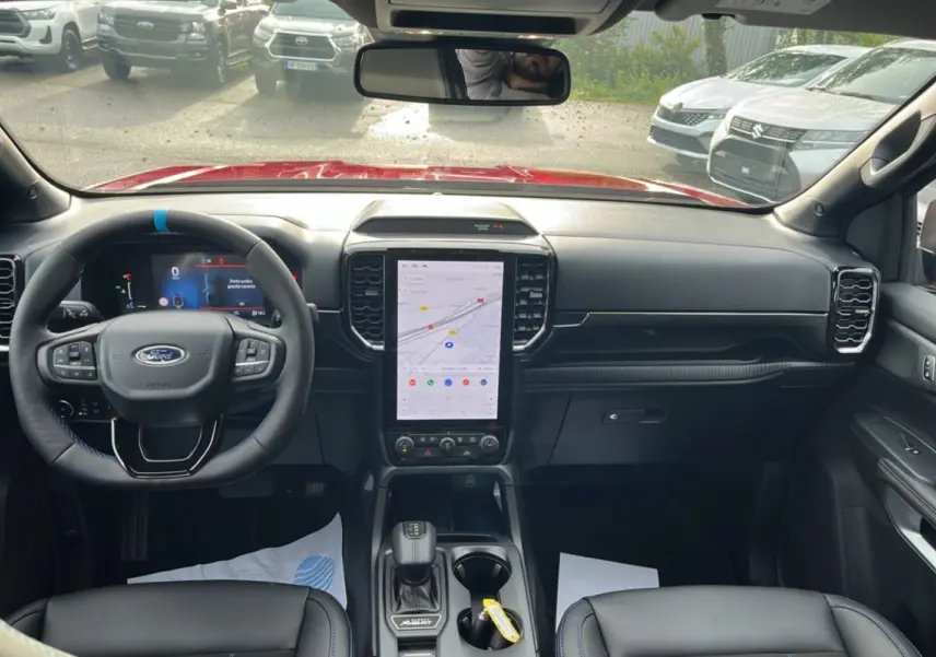 Vue intérieure avant du Ford Ranger 3.0 V6 240 MS-RT PLUS avec tableau de bord noir et écran tactile central vertical.