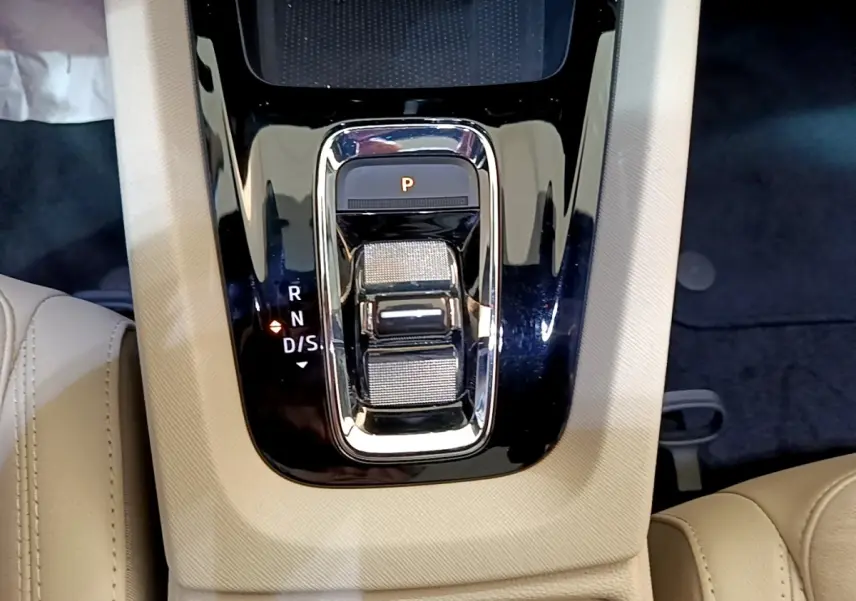 Gros plan sur la commande de boîte automatique noire entourée de cuir beige dans une Skoda Octavia blanche 2022.