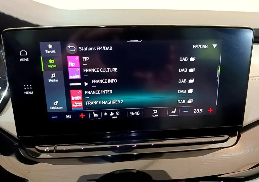Écran tactile central affichant les stations radio FM/DAB dans l'habitacle beige de la Skoda Octavia blanche 2022.