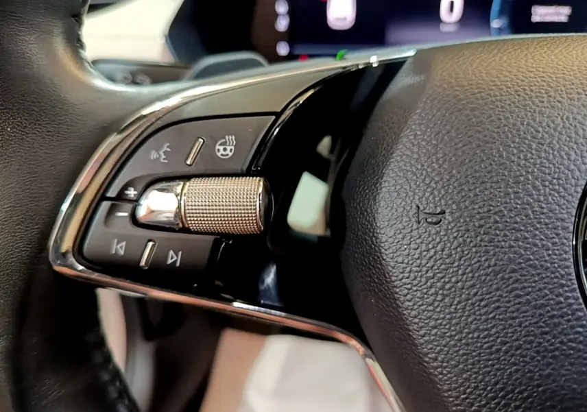 Gros plan sur la molette de contrôle et les boutons du volant noir de la Skoda Octavia 2.0 TDI 2022.