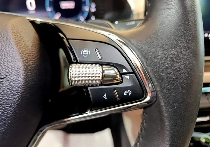 Gros plan sur les commandes en chrome et noir du volant cuir d'une Skoda Octavia blanche 2022, version Style.