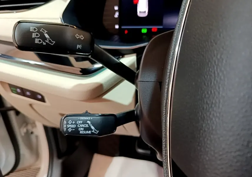 Gros plan sur les commandes de clignotants et régulateur au volant cuir noir de la Skoda Octavia blanche 2022.