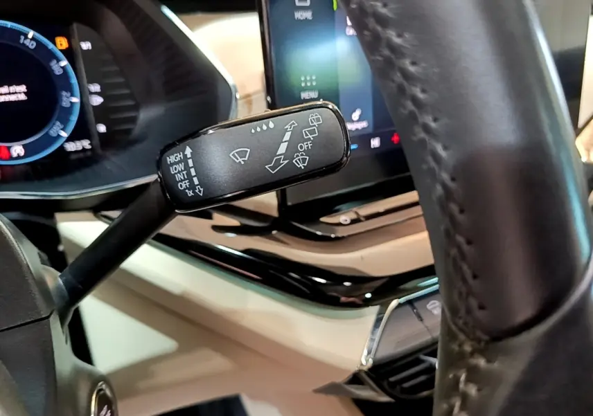 Gros plan sur la commande d'essuie-glace à gauche du volant cuir dans l'habitacle beige d'une Skoda Octavia blanche 2022.