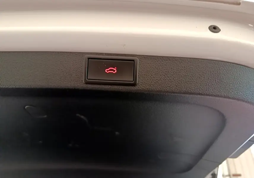 Bouton d'ouverture du coffre rouge sur la garniture intérieure blanche d'une Skoda Octavia 2.0 TDI 2022.