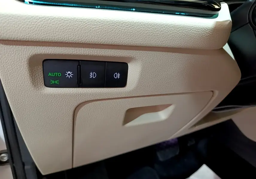 Gros plan sur les commandes d’éclairage automatiques intégrées dans la planche de bord beige de la Skoda Octavia blanche 2022.