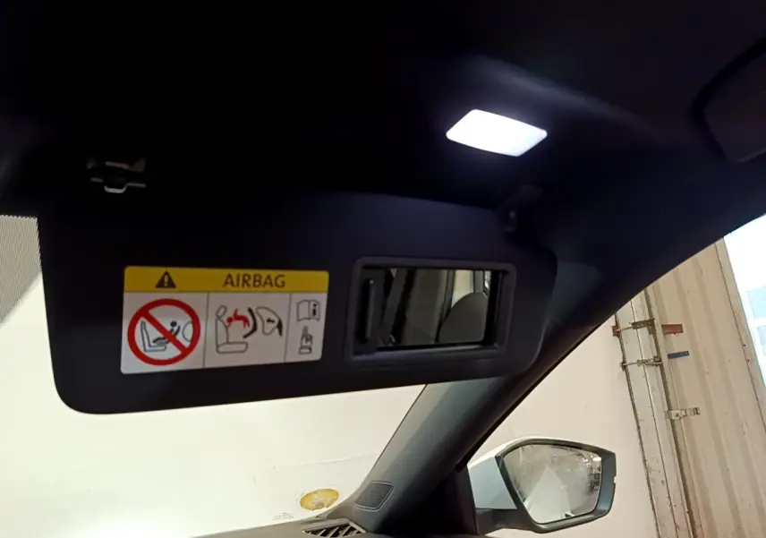 Détail du pare-soleil côté conducteur avec miroir intégré et avertissement airbag dans une Skoda Octavia blanche 2022.