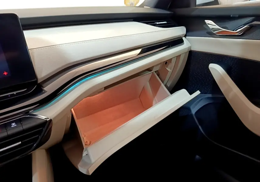 Intérieur beige clair de la Skoda Octavia 2022, vue sur la boîte à gants ouverte côté passager avec éclairage ambiant bleu.