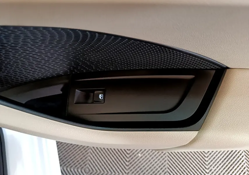 Gros plan sur la commande de lève-vitre côté conducteur dans l'intérieur beige d'une Skoda Octavia 2022 blanche.