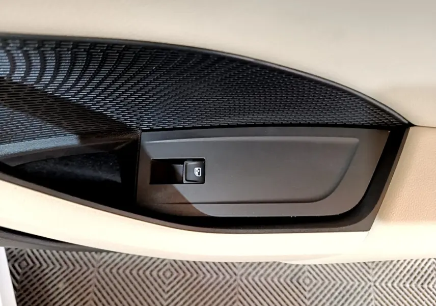 Gros plan sur la commande de verrouillage de porte noire intégrée dans la garniture beige intérieure d'une Skoda Octavia blanche.