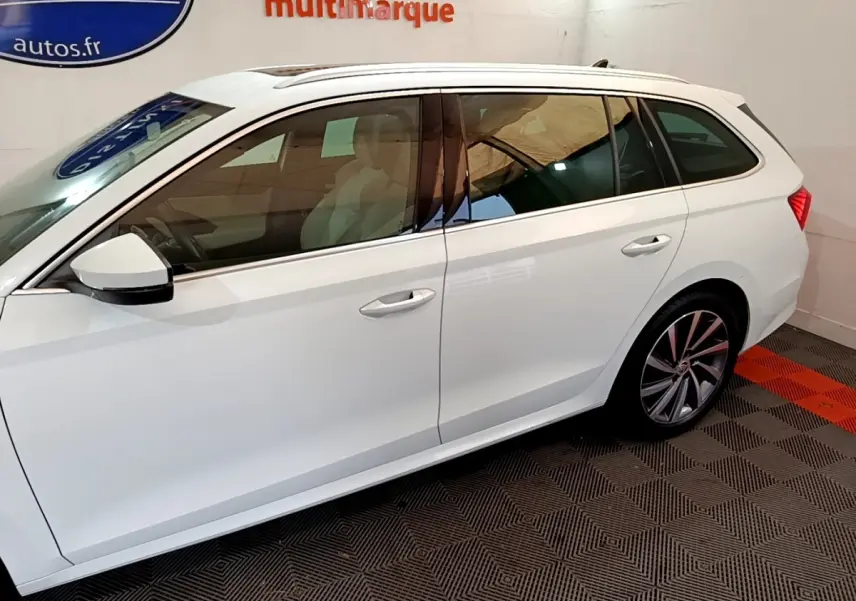 Vue latérale côté gauche d'une Skoda Octavia break blanche avec jantes alliage et vitres teintées.