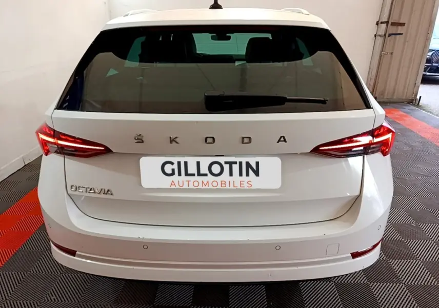 Vue arrière d'une Skoda Octavia blanche 2022 avec feux LED allumés et logo apparent sur un sol à damiers rouge et noir.