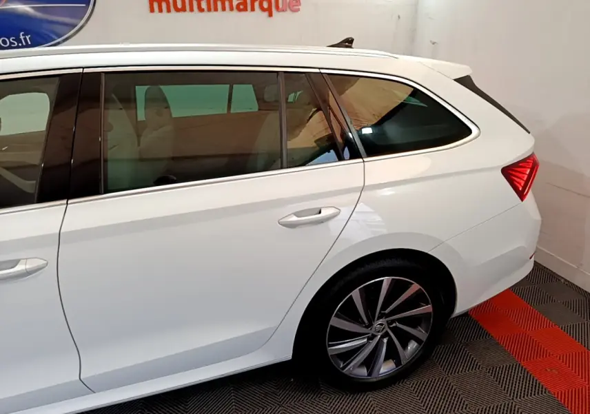 Vue latérale côté droit d'une Skoda Octavia blanche, mettant en valeur la roue arrière et la lunette teintée.