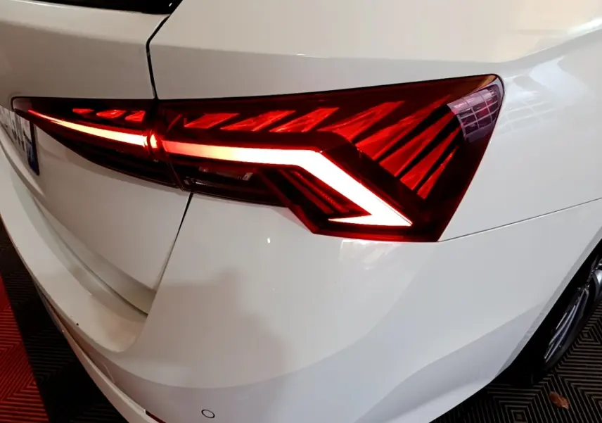 Gros plan sur le feu arrière droit allumé d'une Skoda Octavia blanche, soulignant ses lignes LED distinctives.
