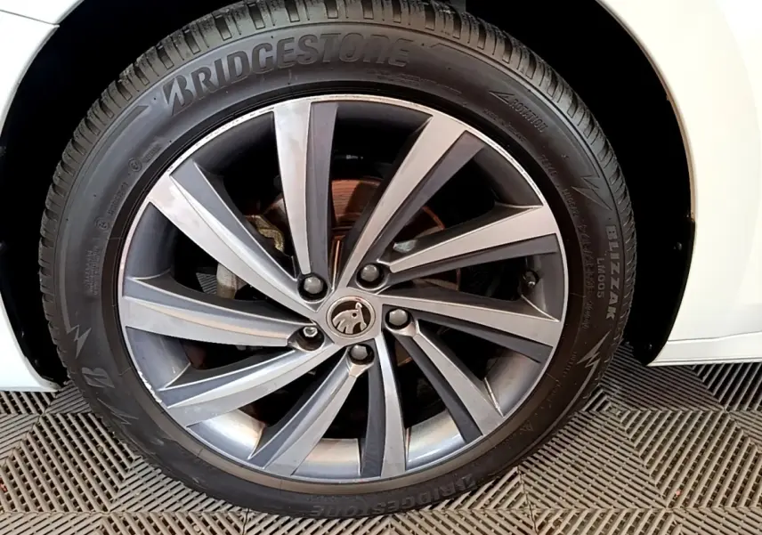 Gros plan sur la roue avant gauche blanche d’une Skoda Octavia 2.0 TDI 150 DSG7 Style avec jante alliage gris foncé.