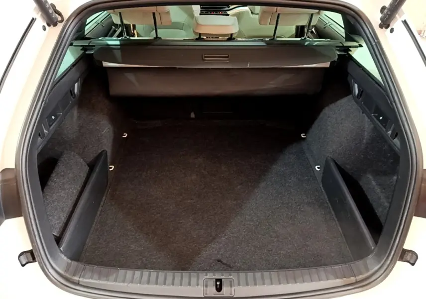 Coffre ouvert vu de l'arrière d'une Skoda Octavia blanche, montrant un espace de chargement vide et bien agencé.