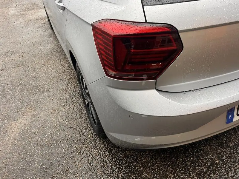 Vue arrière côté gauche d'une Volkswagen Polo gris clair avec feux arrière rouges et jantes alliage.