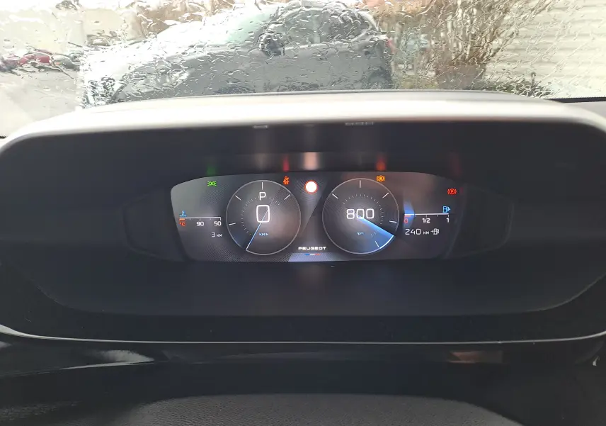 Vue rapprochée du tableau de bord numérique de la Peugeot 308 blanc Okenite, affichant la vitesse à 0 km/h et le régime moteur à 800 rpm.