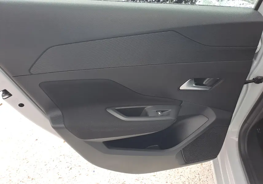 Vue intérieure de la porte arrière droite d'une Peugeot 308 blanche, avec poignée argentée et commande de vitre.