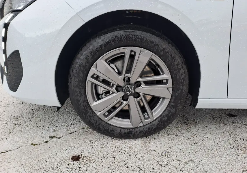 Gros plan sur la roue avant gauche de la Peugeot 308 blanche Okenite avec jante alliage et badge Style sur l'aile.