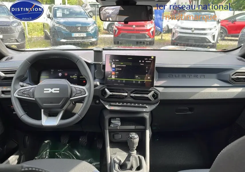 Vue intérieure avant du Dacia Duster gris schiste 2025, tableau de bord moderne avec écran tactile et volant multifonction.