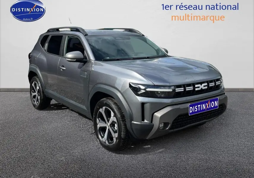 SUV Dacia Duster gris schiste vu en 3/4 avant droit avec barres de toit et jantes alu distinctives.