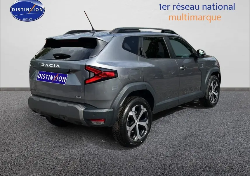 Vue 3/4 arrière droite d'un Dacia Duster gris schiste avec jantes alu et barres de toit noires.