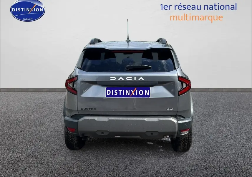 Vue arrière du Dacia Duster gris schiste 2025 avec logo DACIA et badge 4x4 visible sur un fond neutre.