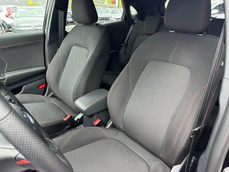 Vue intérieure rapprochée des sièges avant noirs avec surpiqûres rouges du Ford Puma 2024 ST-Line.