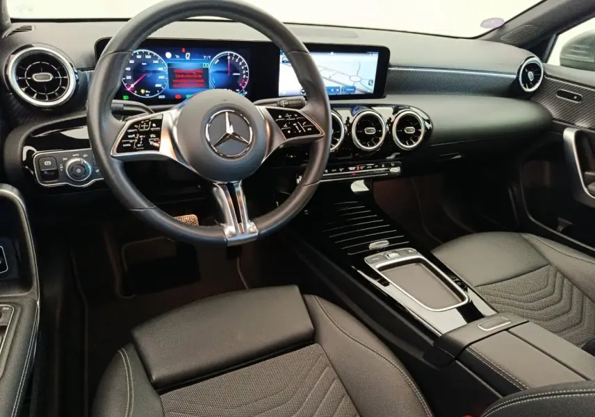 Vue intérieure avant de la Mercedes Classe A 250 e hybride, tableau de bord noir avec écran tactile et volant multifonctions.