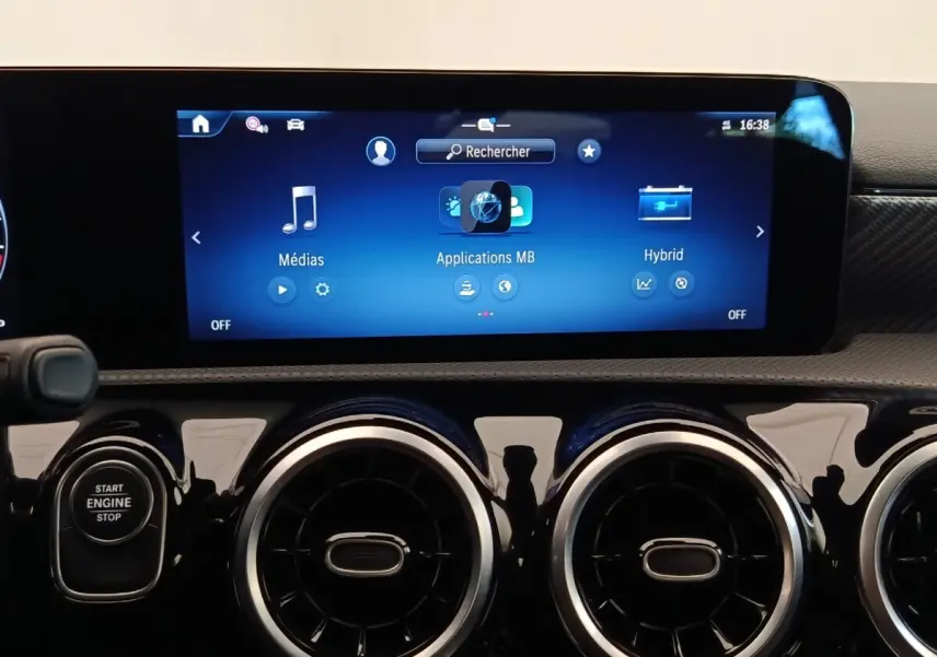 Vue rapprochée du tableau de bord noir brillant de la Mercedes Classe A 250 e Hybrid avec écran tactile multifonctions allumé.