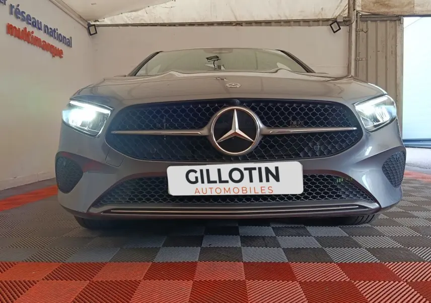Vue frontale d'une Mercedes Classe A 250 e Hybrid gris foncé avec phares LED allumés en intérieur.