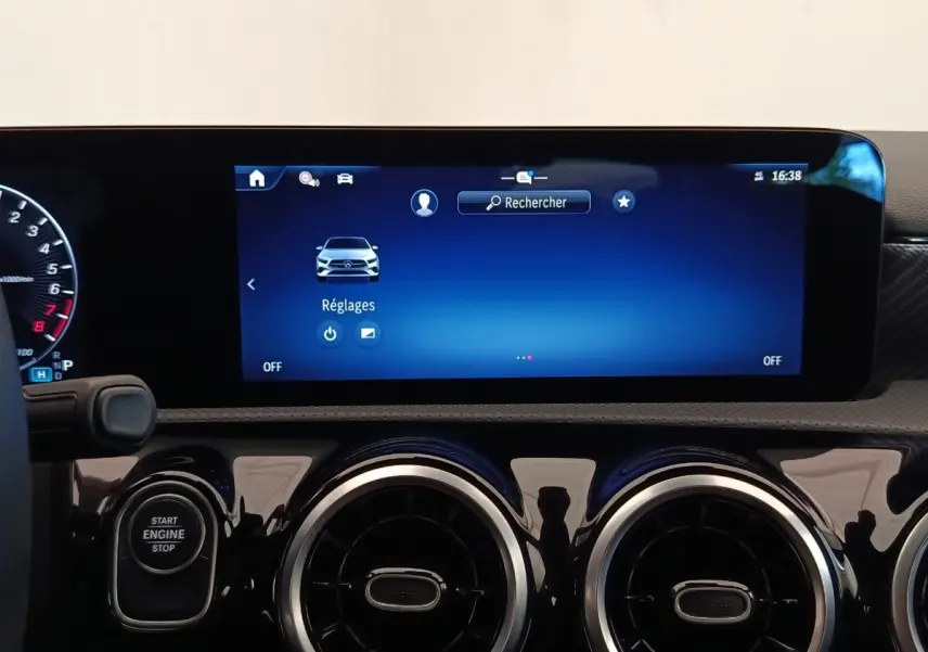 Vue rapprochée du tableau de bord de la Mercedes Classe A 250 e Hybrid avec écran tactile bleu et aérateurs ronds noirs.