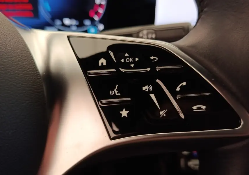 Gros plan sur les commandes tactiles noires du volant côté gauche d’une Mercedes Classe A 250 e hybride 2024.