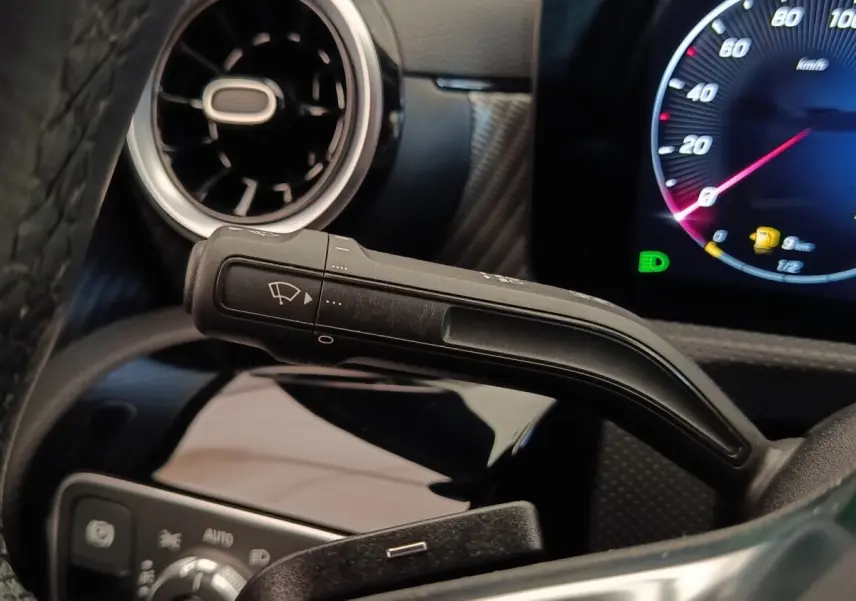 Gros plan sur la manette d’essuie-glace à gauche du volant dans l’habitacle gris foncé de la Mercedes Classe A 250 e Hybrid 2024.