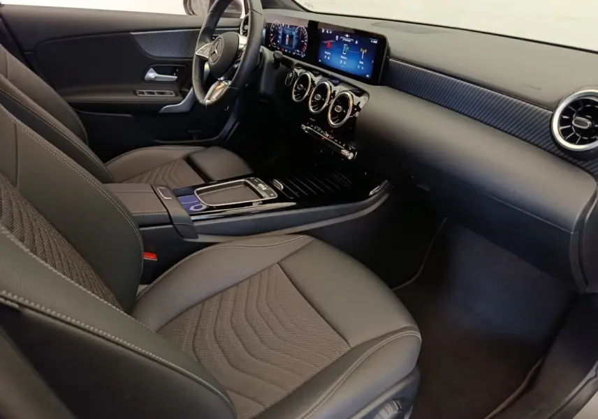 Intérieur avant droit de la Mercedes Classe A 250 e Hybrid 2024, tableau de bord numérique et sièges gris foncé.