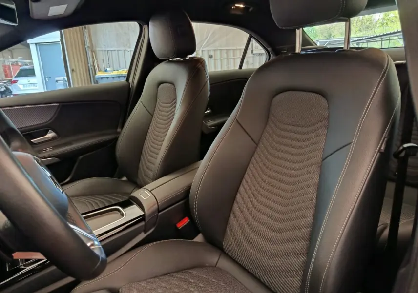 Vue intérieure côté avant droit de la Mercedes Classe A 250 e Hybrid, sièges en cuir noir avec surpiqûres contrastées.