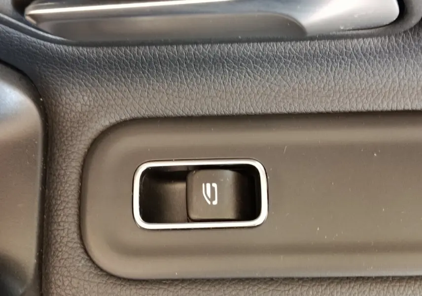 Gros plan sur le bouton de commande de la fermeture électrique du hayon dans l’habitacle gris foncé de la Mercedes Classe A 250 e Hybrid.