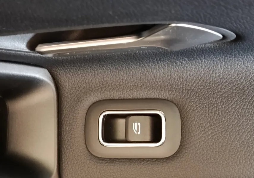 Gros plan sur la commande de lève-vitre électrique côté conducteur, entourée de cuir noir texturé.