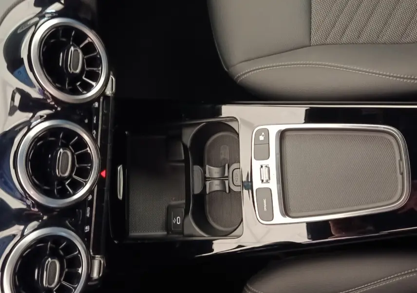 Vue plongeante sur la console centrale noire brillante de la Mercedes Classe A 250 e Hybrid avec aérateurs ronds chromés.