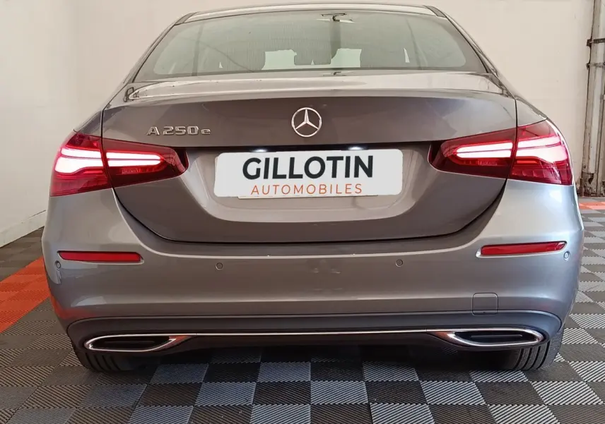 Vue arrière d'une Mercedes Classe A 250 e hybride rechargeable gris foncé avec feux LED allumés et double sortie d'échappement chromée.