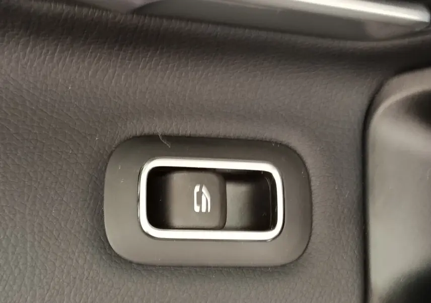 Bouton de commande de hayon électrique sur panneau intérieur noir d'une Mercedes Classe A 250 e Hybrid gris foncé.