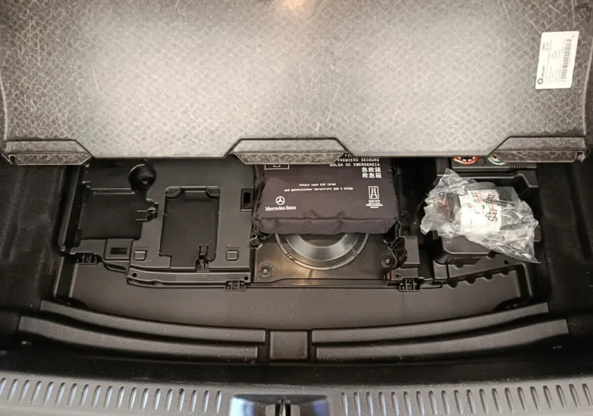 Vue plongeante sur le compartiment de rangement sous le plancher du coffre de la Mercedes Classe A 250 e gris foncé.