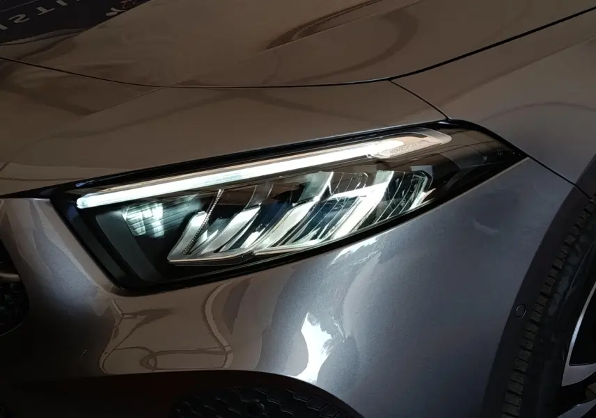 Gros plan sur le phare avant droit d’une Mercedes Classe A 250 e Hybrid gris foncé 2024, détails LED visibles.