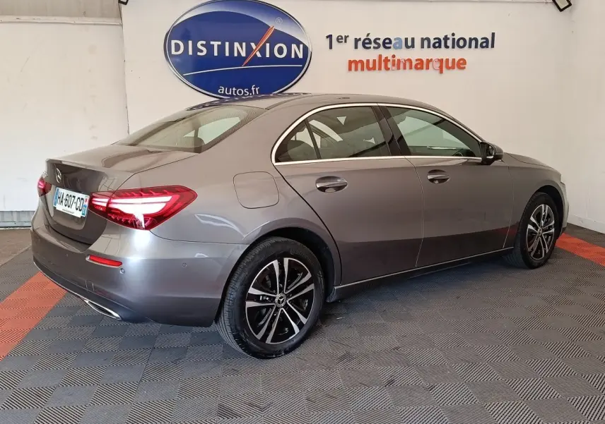 Vue 3/4 arrière droite d'une Mercedes Classe A 250 e hybride rechargeable gris foncé avec feux LED allumés.