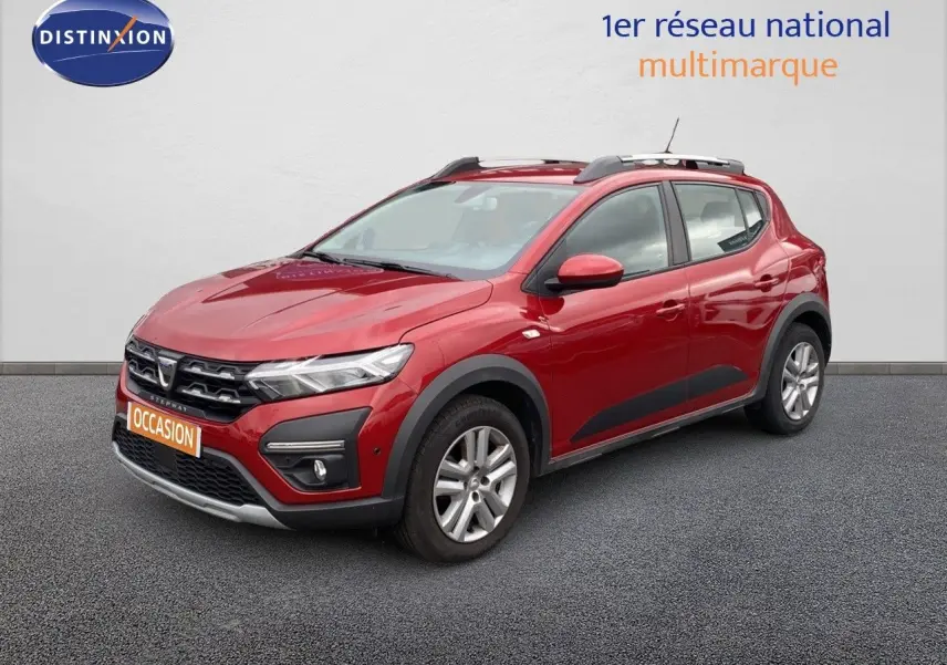 Dacia Sandero Stepway rouge fusion métal en 3/4 avant droit, avec protections noires et barres de toit visibles.