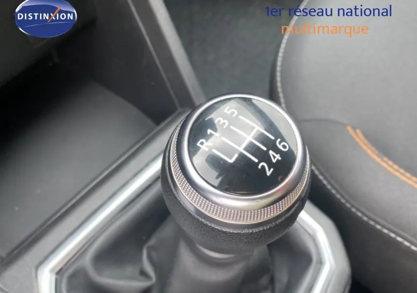 Gros plan sur le levier de vitesses manuel de la Dacia Sandero Stepway rouge fusion, avec coutures orange visibles sur le siège.