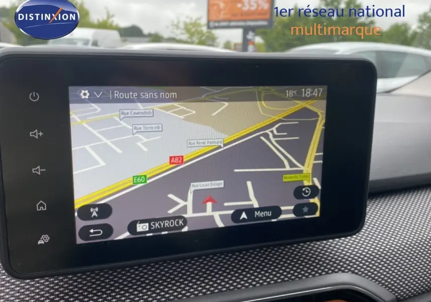 Écran tactile central du tableau de bord de la Dacia Sandero rouge, affichant la navigation GPS en extérieur.