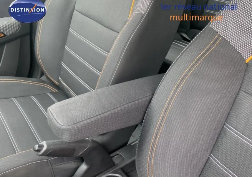Gros plan sur l'accoudoir central et les sièges avant en tissu gris avec surpiqûres orange du Dacia Sandero Stepway 2022.